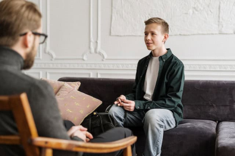 Young Man Speaking to Therapist Learning Holistic Therapy vs Psychiatric Medicine