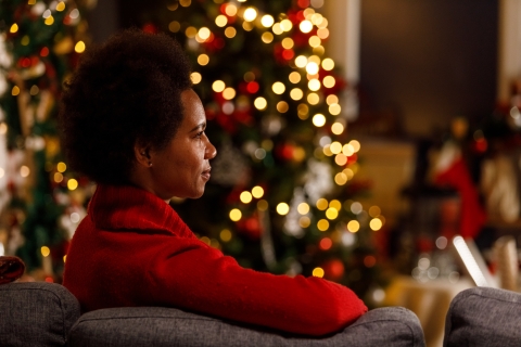 Woman sitting on a couch in front of a Christmas tree